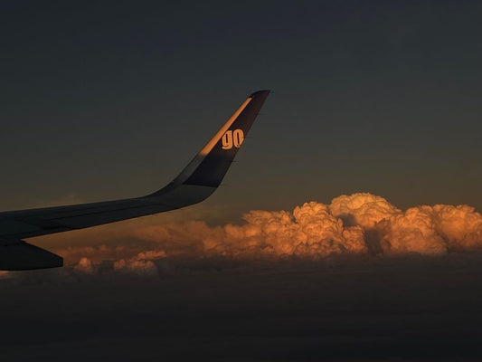 Airplane wing above clouds at sunrise