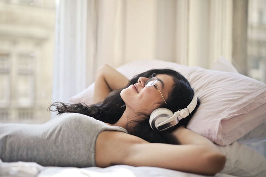 A person relaxing on a bed while listening to headphones
