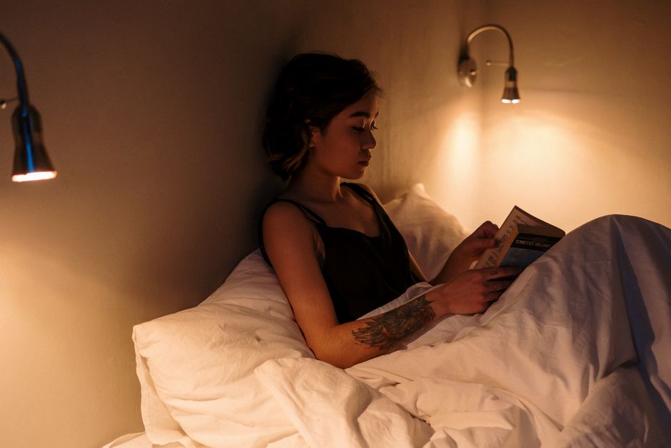 Woman reading in bed under warm lamp light