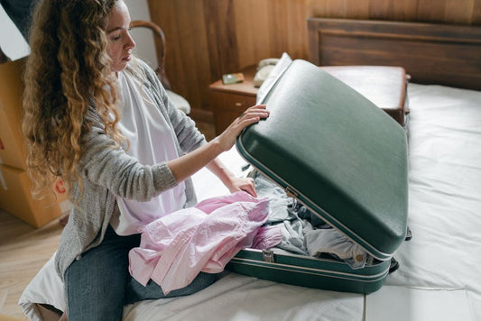 Traveller packing a suitcase on a bed