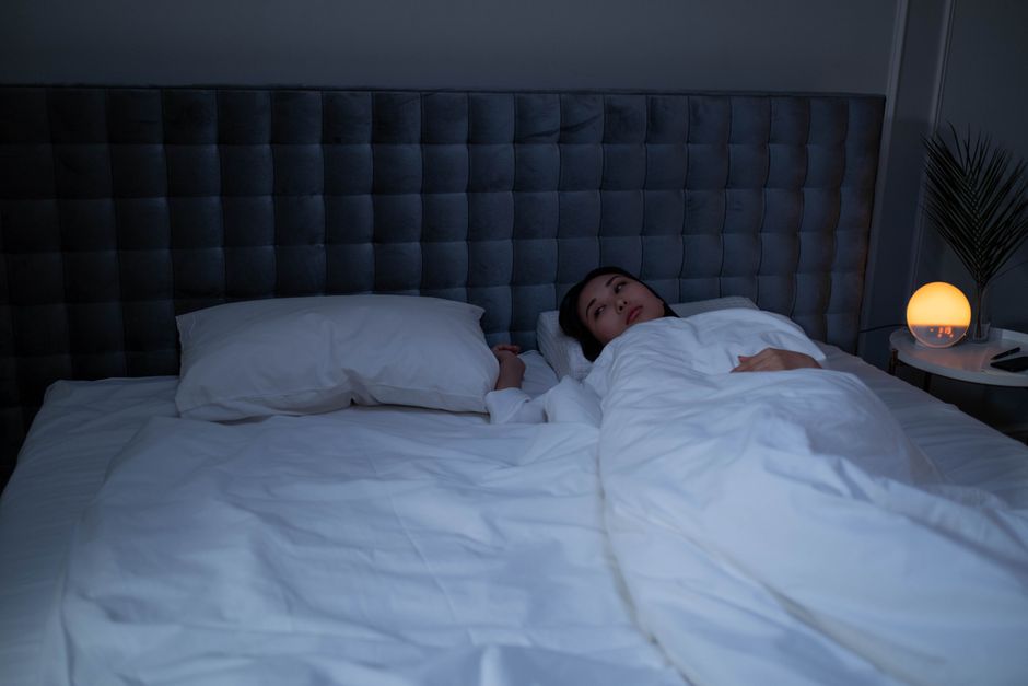 Woman lying awake in a dim bedroom at night